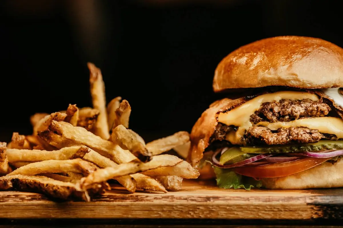 Burger mit Pommes auf einem Holzbrett