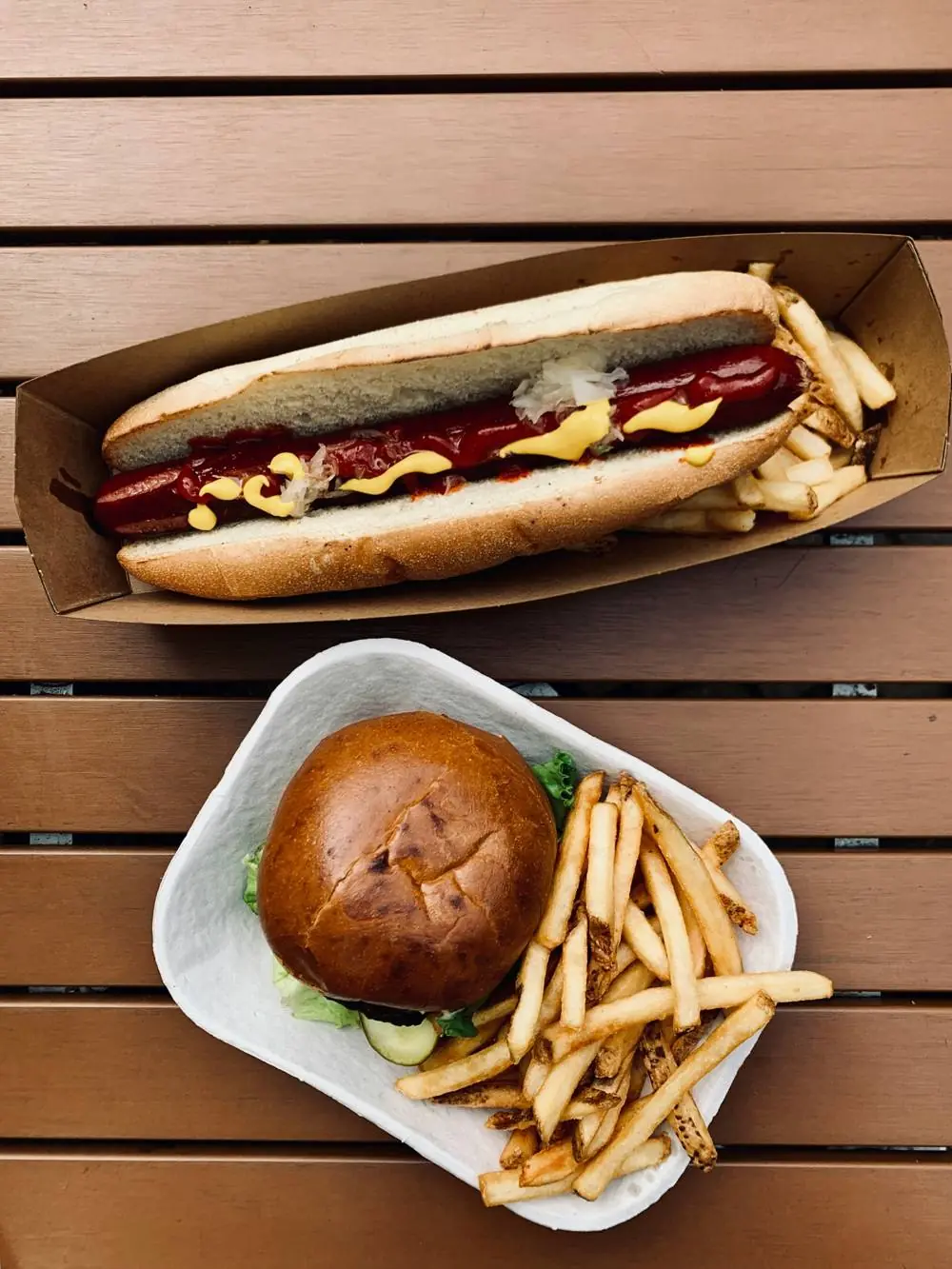 Hotdog und Burger mit Pommes in Papierschalen